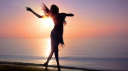 Die erlöste feminine Energie Frau die bei Sonnenaufgang am Strand tanzt