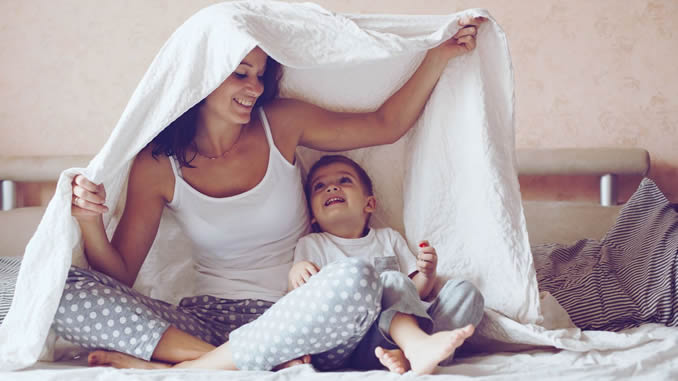Mutter hält schützend eine Decke über ihr Kind