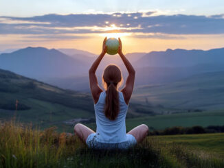 Sitzende Frau auf einer Wiese hält eine Weltkugel hoch