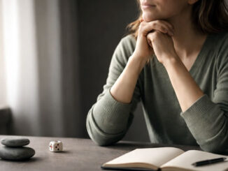 eine Frau sitzt am Schreibtisch mit Block und Würfel