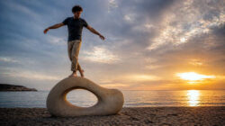 Unternehmerischer Erfolg - Balance an Strandskulptur bei Sonnenuntergang