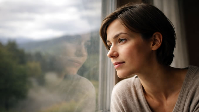 Nachdenklicher Blick einer Frau aus dem Fenster