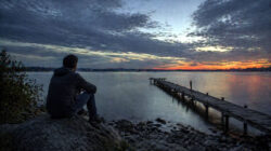 Körper als Spiegel Mann sitzt nachdenklich am Ufer eines Sees