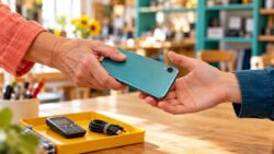 alte Handys entsorgen - ein gebrauchtes Smartphone wird von einer Hand zur anderen weitergegeben
